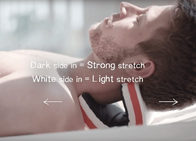 This is a close up image of a man with dark hair and a closely trimmed beard lying on a necksaviour. Overwritten on the photo in white are two arrows one facing to the left and one to the right. Above are the words dark side in = strong stretch and below that white side in = light stretch.