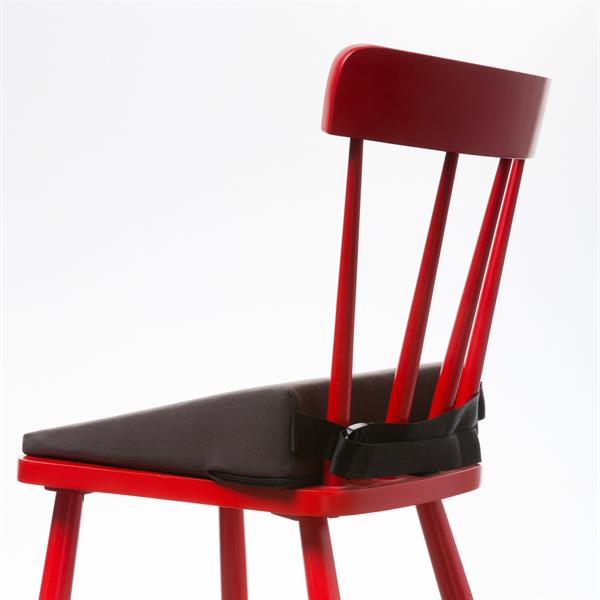 A red wooden chair is at an angle facing away. On it you can see the harley wedge and the strap tightened around the back of the chair keeping if firmly in place.