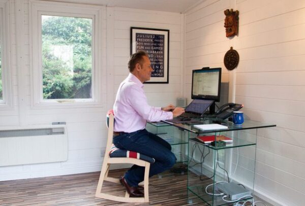 A man sat at his computer desk on a Union Jack covered RockBack chair.