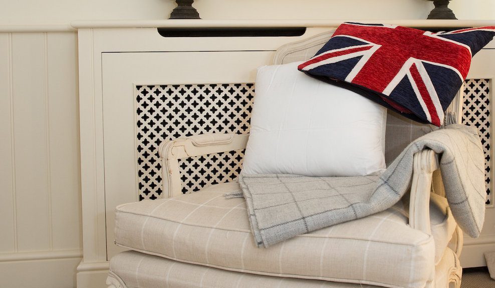 Our Top Three Back Support Cushions For The Sofa A homely scene. The background is cream as is the deep chair, the fabric of which has white stripes horizontally and vertically. Drapped over the back of the chair is a union jack cushion cover and leaning against the back of the chair is a Sittingwell back support for the sofa and deep chairs similar to the one it is displayed on. The Sittingwell cushion does just look like a white square - the inside of a cushion before the cover goes on, that's the magic of it, noone ever knows and your home looks as fab as ever.