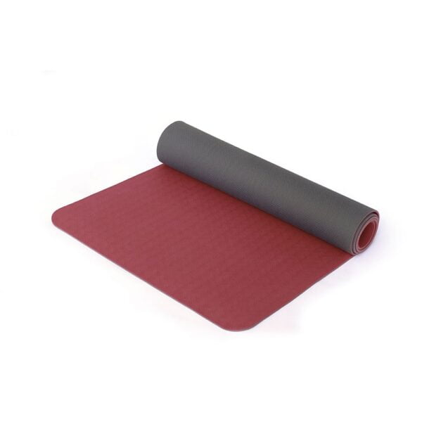 A Sissel terra yoga mat that is half rolled up so you can see the grey underside, the rest of the yoga mat is laid out flat. It is burgundy. The background is plain white