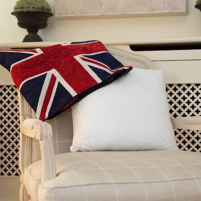 A homely scene. The background is cream as is the deep chair, the fabric of which has white stripes horizontally and vertically. Drapped over the back of the chair is a union jack cushion cover and leaning against the back of the chair is a Sittingwell back support for the sofa and deep chairs similar to the one it is displayed on. The Sittingwell cushion does just look like a white square - the inside of a cushion before the cover goes on, that's the magic of it, noone ever knows and your home looks as fab as ever