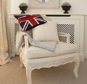 Sittingwell Cushion on a deep cream chair. Drapped over the back of the chair is a union jack cushion cover and leaning against the back of the chair is a Sittingwell back support for the sofa and deep chairs similar to the one it is displayed on. The Sittingwell cushion does just look like a white square - the inside of a cushion before the cover goes on, that's the magic of it, no one ever knows and your home looks as fab as ever