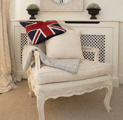 Sittingwell Cushion on a deep cream chair. Drapped over the back of the chair is a union jack cushion cover and leaning against the back of the chair is a Sittingwell back support for the sofa and deep chairs similar to the one it is displayed on. The Sittingwell cushion does just look like a white square - the inside of a cushion before the cover goes on, that's the magic of it, no one ever knows and your home looks as fab as ever